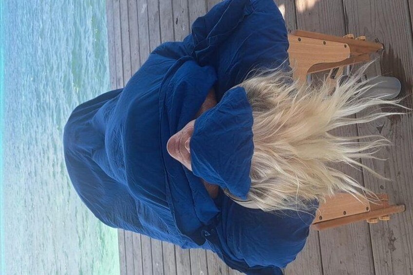 A person sitting on a wooden deck by the water. 4