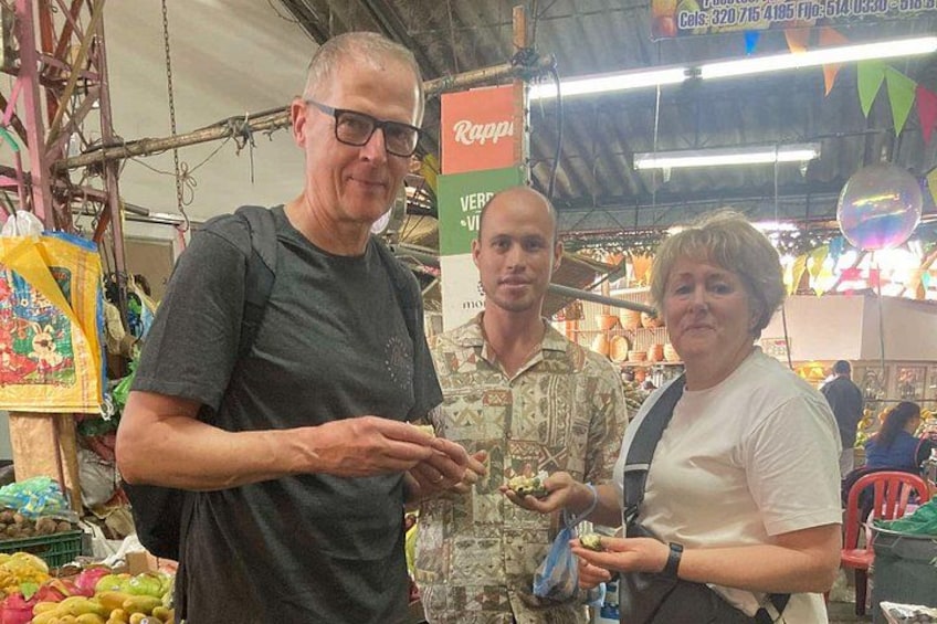 Three people at a market stall with various fruits and vegetables on display. 4