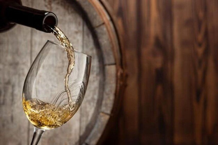 Una copa de vino siendo llenada con un líquido dorado, probablemente vino, desde una botella. 2