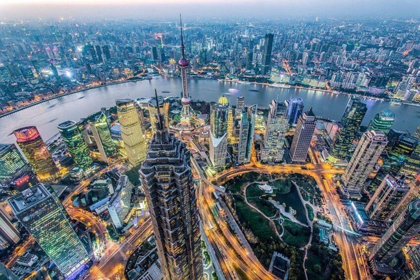 A cityscape with a prominent tower, dense high-rise buildings, a river, and a roundabout. 5