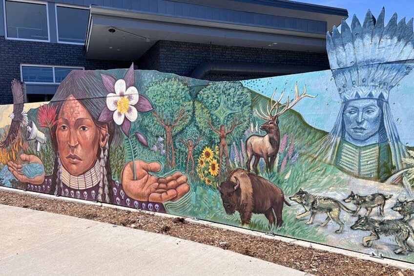 A mural with indigenous figures, animals, and a totem pole. 1
