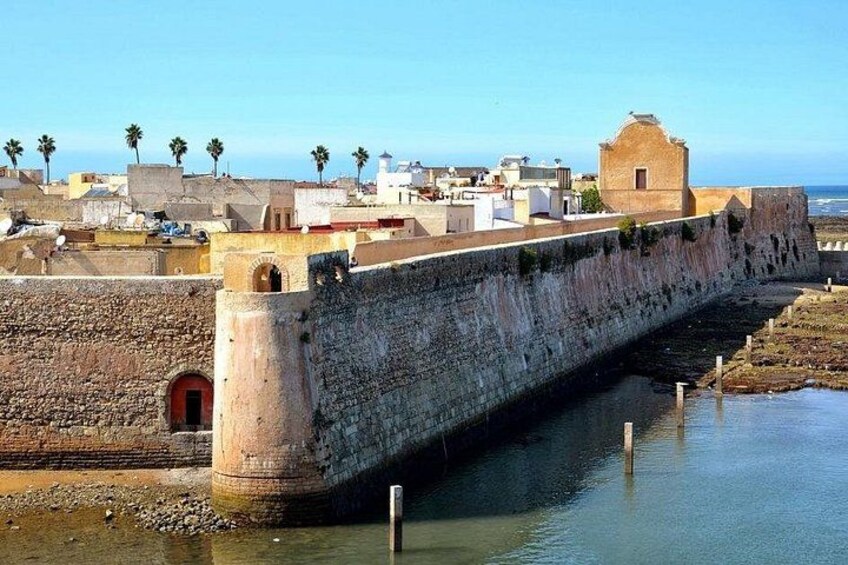 A stone bridge over water, a coastal town with buildings, and palm trees. 3