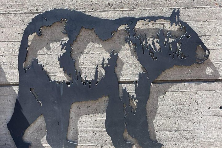 Una escultura de metal de un oso sobre una pared con textura. 2