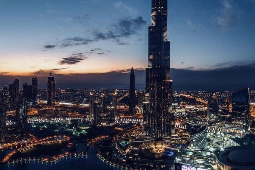 A cityscape at dusk with a prominent skyscraper, illuminated buildings, and a network of roads. 2