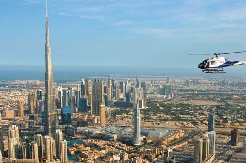 A cityscape with a prominent skyscraper, a helicopter in flight, and a body of water in the distance. 4