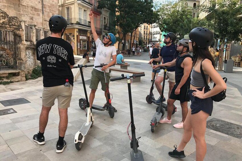 Mensen rijden op elektrische scooters in een stedelijke omgeving met historische gebouwen. 1