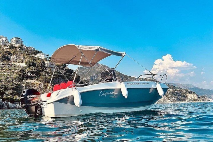 A boat named 'Capitan' anchored near a rocky coastline with buildings in the background. 4