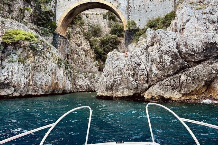 A boat approaching a stone bridge over a rocky waterway. 5