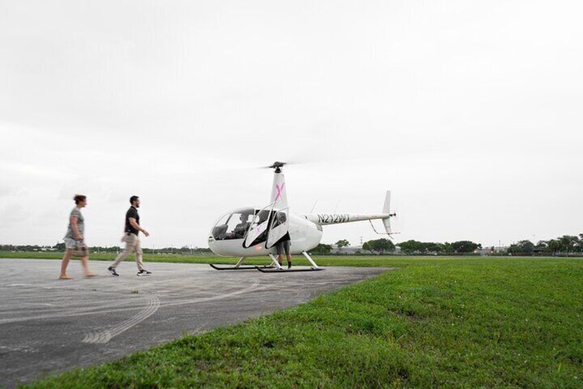 En hvid helikopter på en startbane med to personer, der går ved siden af. 4