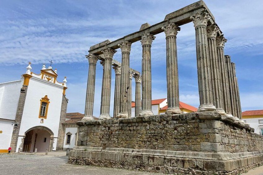 Ancient columns, a white building with yellow trim, and a clear blue sky. 1