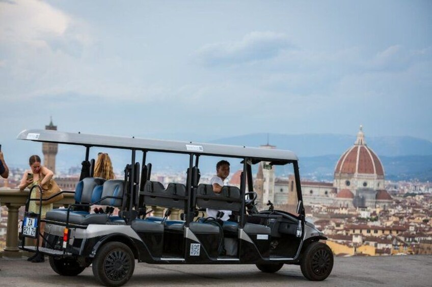 A golf cart with passengers, a dome-shaped building, and a tower in the background. 4