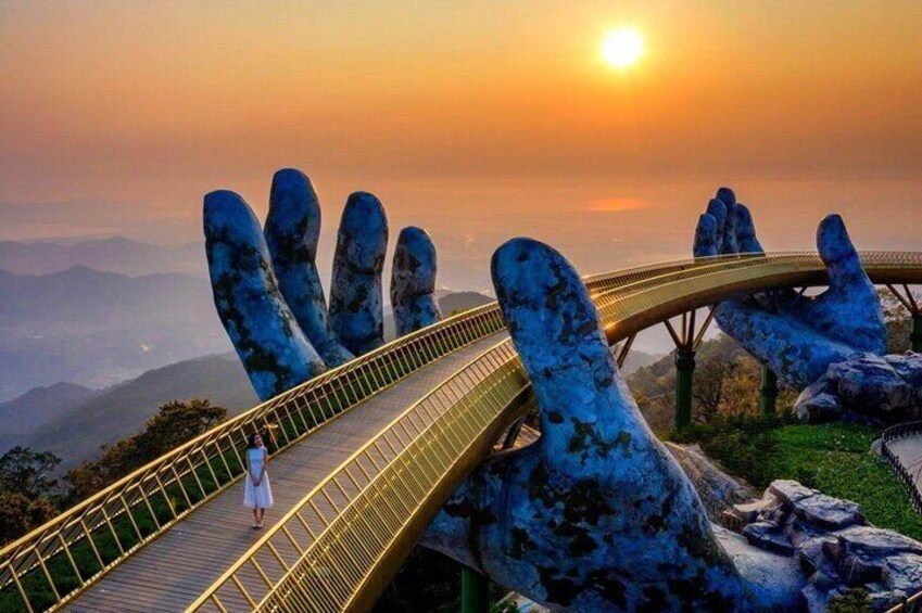 A bridge with a unique hand-shaped design, a person walking, and a sunset in the background. 1