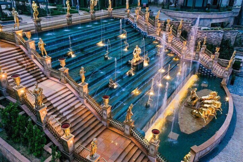 A grand fountain with multiple tiers and statues, surrounded by ornate railings and steps. 4