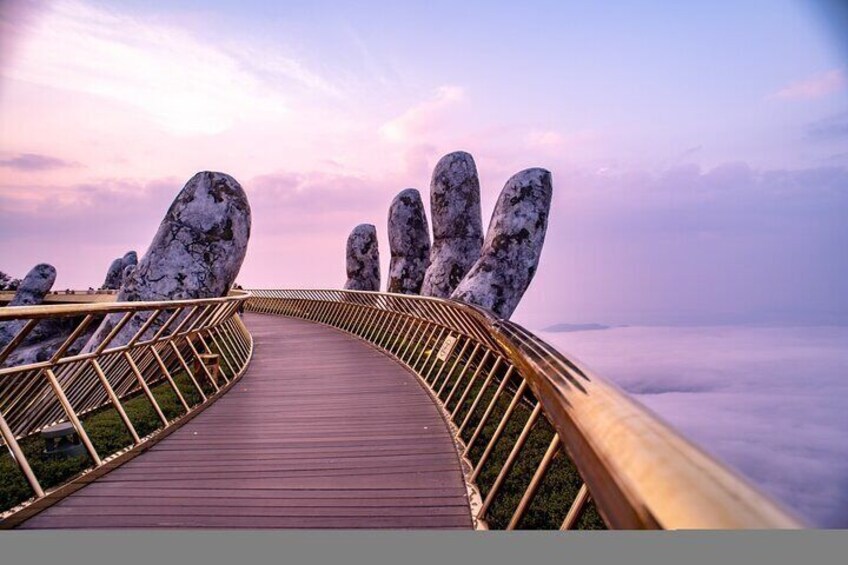 A wooden boardwalk with a metal railing, leading towards large rock formations. 2