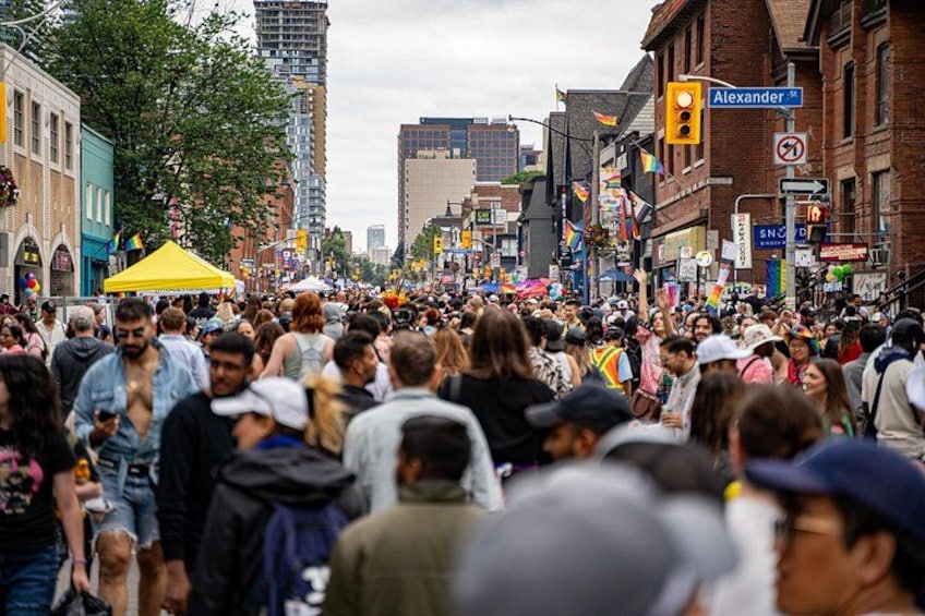 Una calle concurrida con gente caminando, edificios y una carpa amarilla. 3