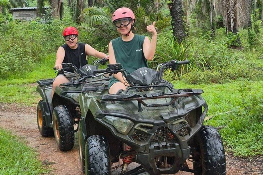 Two people on an ATV in a green, tropical environment. 2
