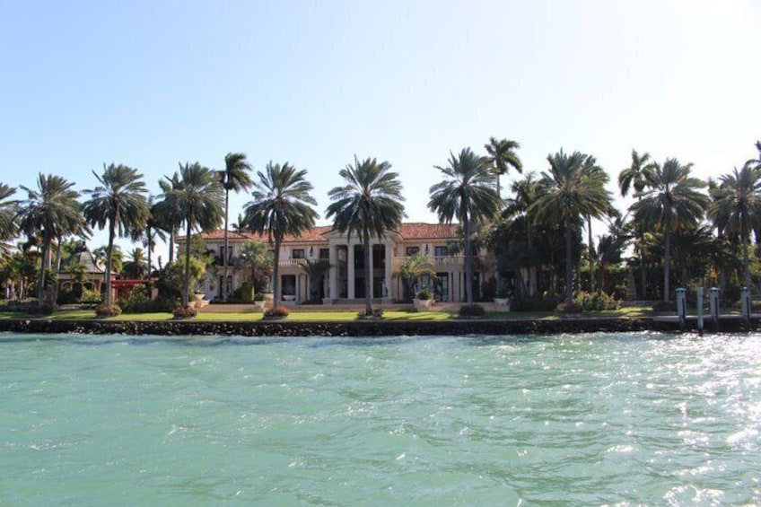 A waterfront property with a large building, palm trees, and a clear blue sky. 4