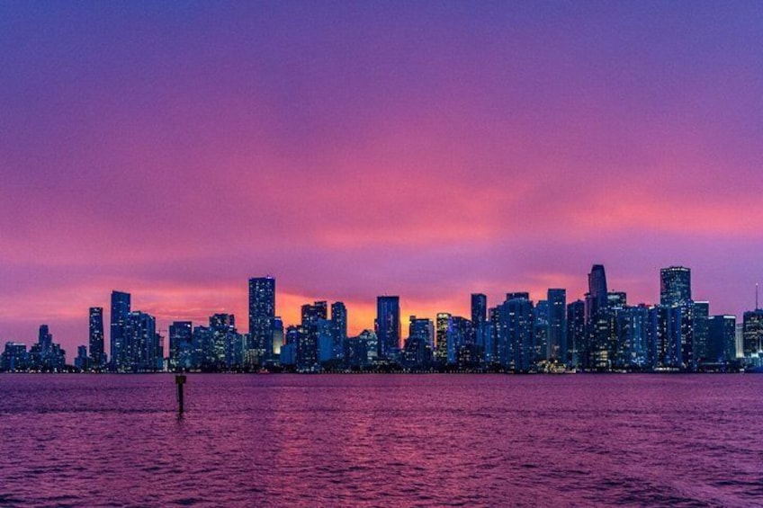 A city skyline at dusk with buildings silhouetted against a purple sky. 5