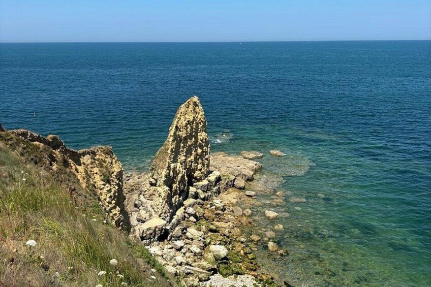 Un paysage côtier caractérisé par une formation rocheuse imposante et une mer d’un bleu limpide. 5
