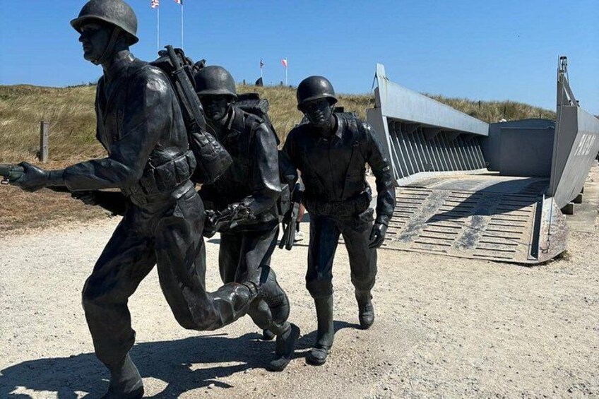 Une statue militaire représentant des soldats en uniforme, un grand avion et un champ d’herbe. 4