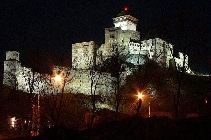 A castle illuminated at night with a prominent tower and surrounding trees. 5