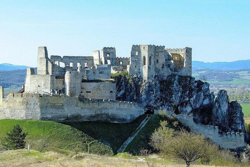 A historic castle with ruins, a moat, and a hilly landscape. 3