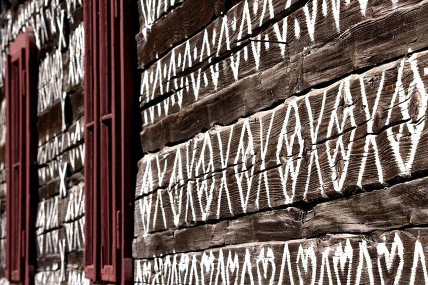 A wooden wall with geometric patterns and red window frames. 4