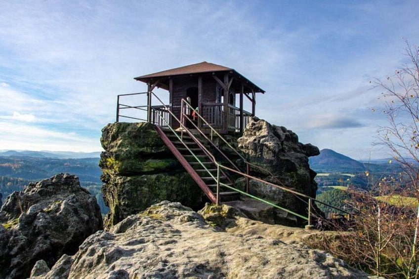 Una torre di osservazione in legno su una sporgenza rocciosa, con una scala che vi conduce. 2