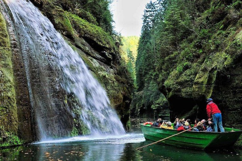 Una cascata, un’imbarcazione verde con persone e una zona boschiva. 4