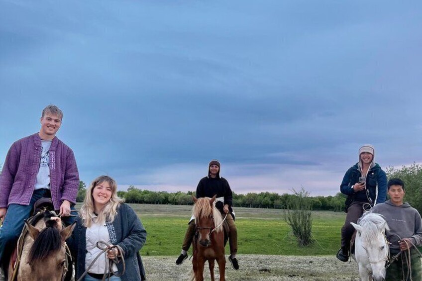 Un gruppo di persone a cavallo in un campo aperto, con cielo nuvoloso. 5