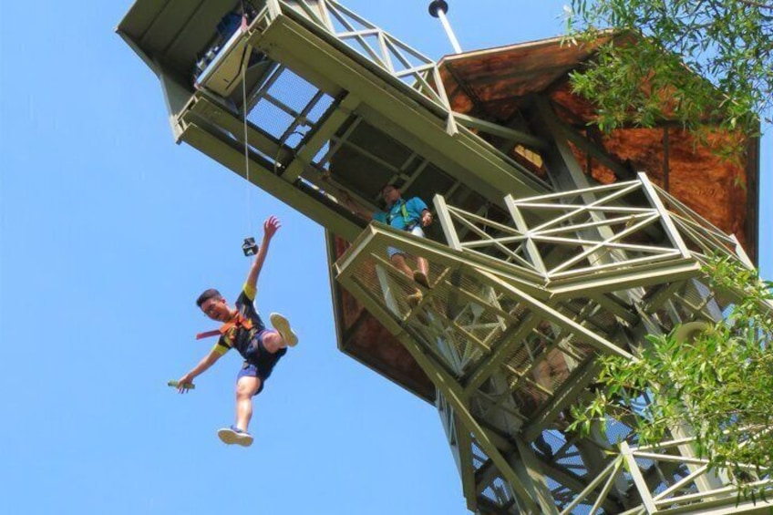 Une personne pratiquant le saut à l’élastique depuis une plateforme élevée, dotée d’une structure en bois et de garde-corps métalliques. 5