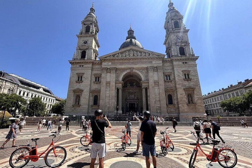 A historic building with two towers, a large open plaza, and several bicycles. 3
