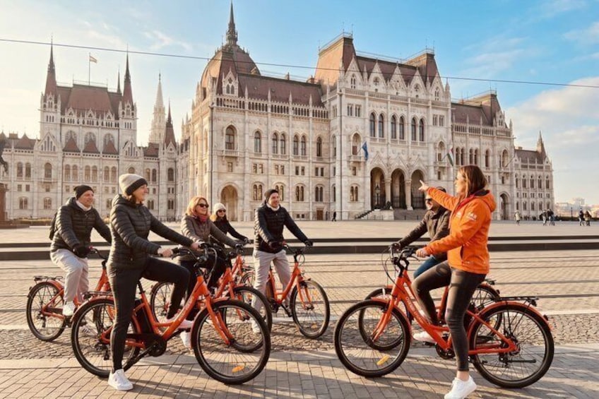 Un gruppo di persone in bicicletta davanti a un grande edificio sfarzoso con guglie. 2