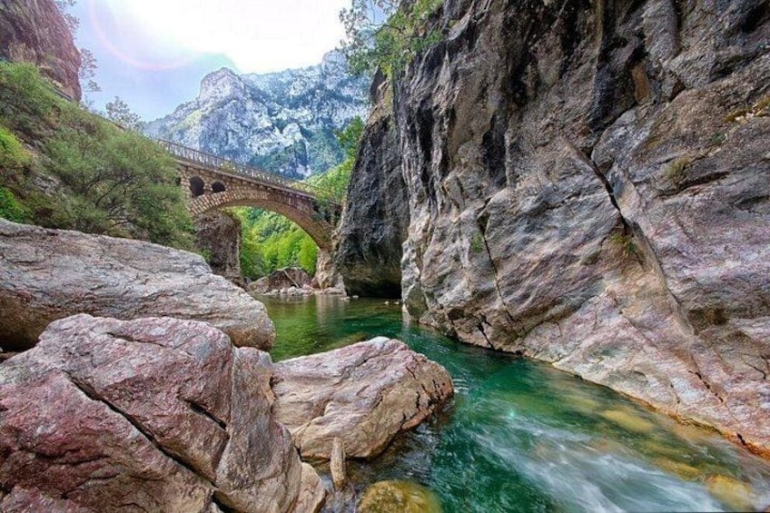 A river flowing through a rocky gorge with a stone bridge. 1