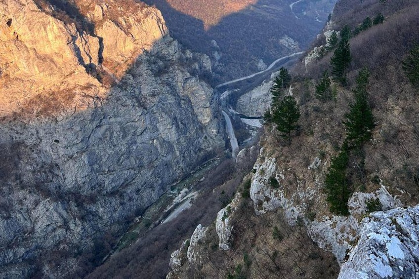 A mountainous landscape with a river, rocky cliffs, and sparse vegetation. 3