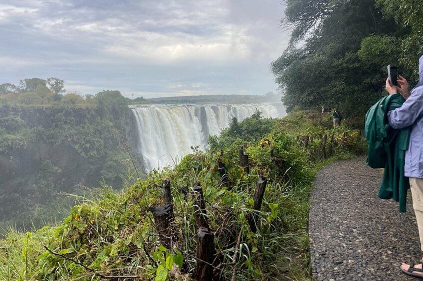 A waterfall, a pathway, and a person taking a photo. 3