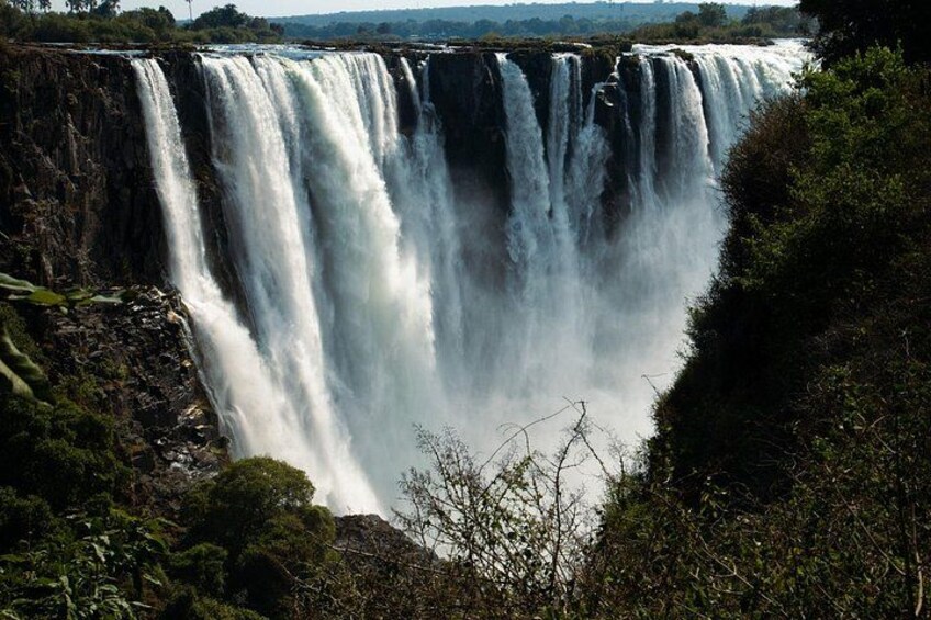 A large waterfall cascading down a rocky cliff surrounded by dense vegetation. 2