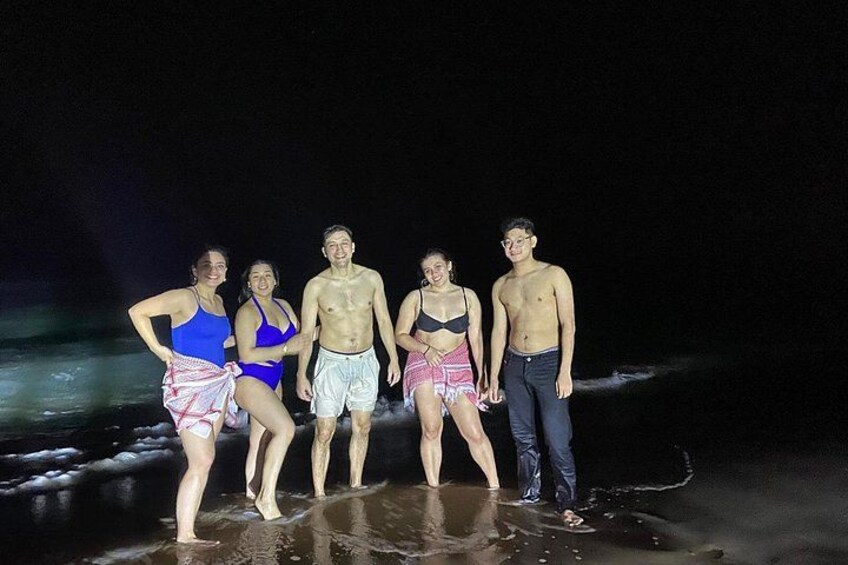 A group of people standing on a beach at night. 2