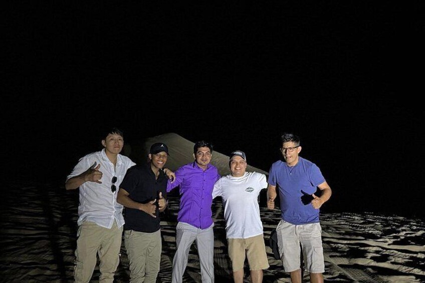 A group of people standing on a sandy beach at night. 4