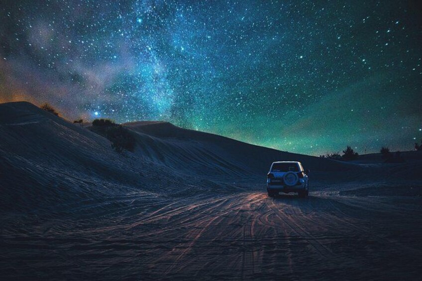 A car on a dirt road under a starry night sky. 1