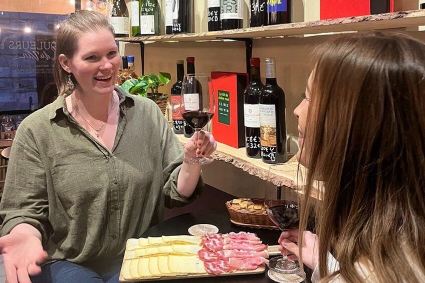 Two people sitting at a table with a charcuterie board and wine bottles. 2