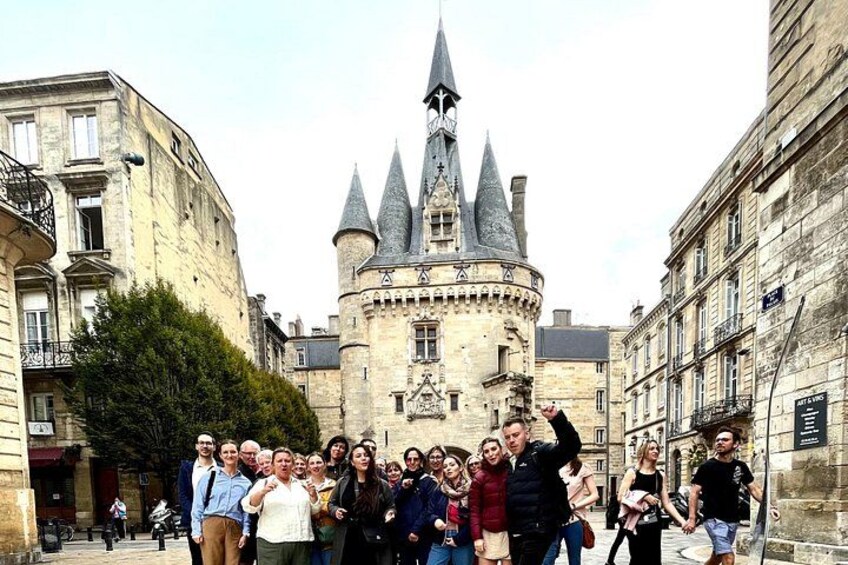 A group of people standing in front of a historic building with a tower. 3