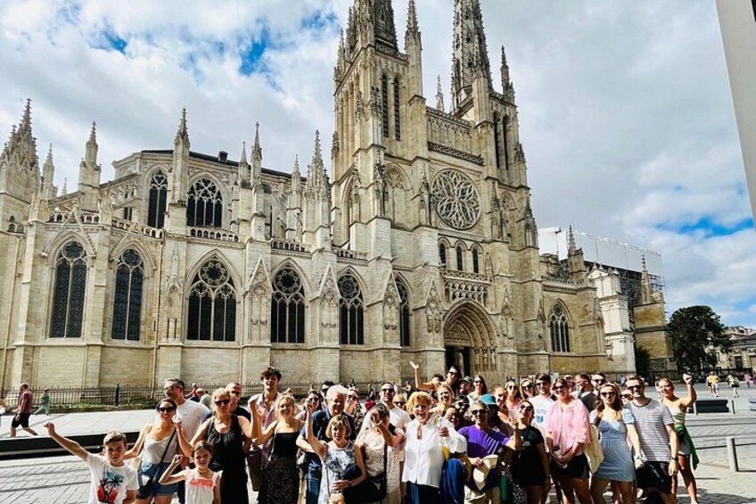 A large crowd of people in front of a historic cathedral with tall spires and large windows. 1