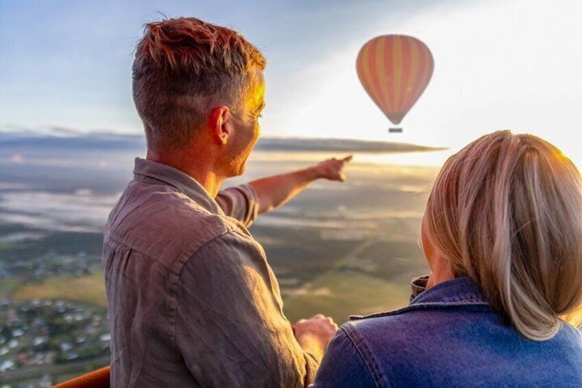 A couple overlooking a landscape with a hot air balloon in the distance. 1