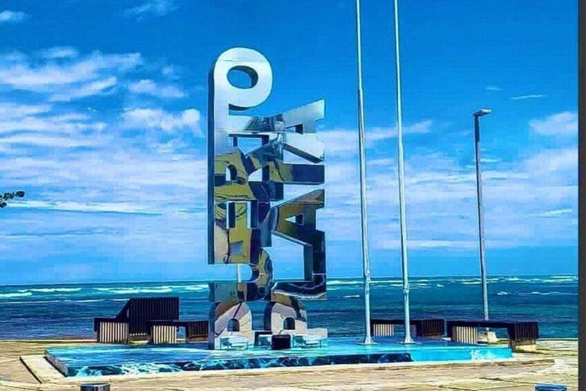 Une sculpture moderne, avec un grand « P » placé sur une plage, l’océan servant de toile de fond. 3