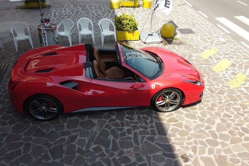 Een rode cabriolet sportauto geparkeerd op een geplaveid straatje. 3