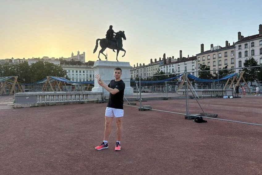 Una persona in piedi su un campo sportivo, con una statua sullo sfondo. 2