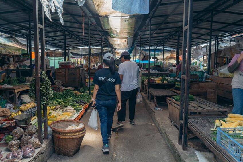 An indoor market with people walking through aisles of fresh produce. 5