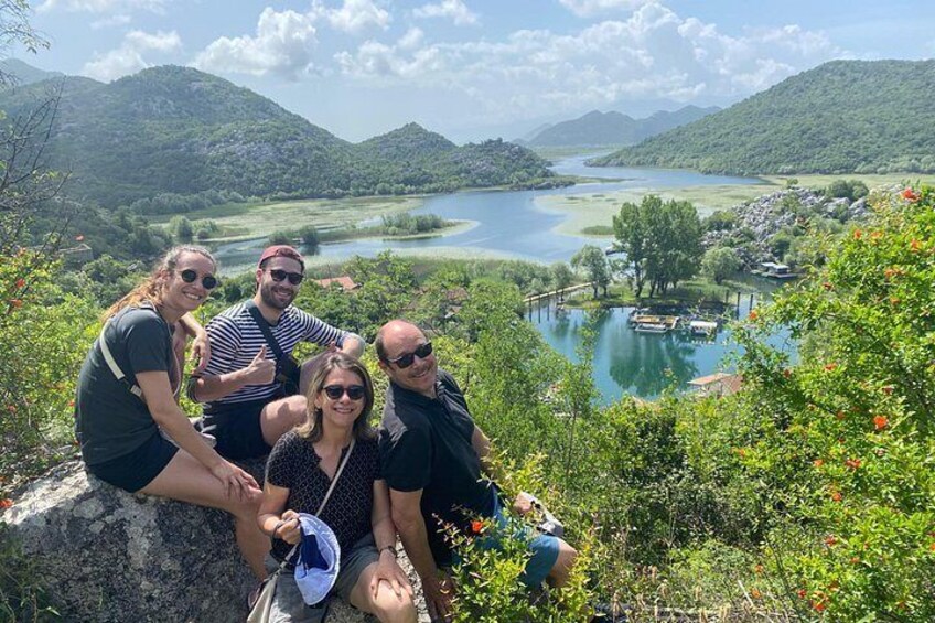 Un groupe de personnes est assis sur un rocher, d’où elles dominent un lac entouré de verdure et de collines. 3