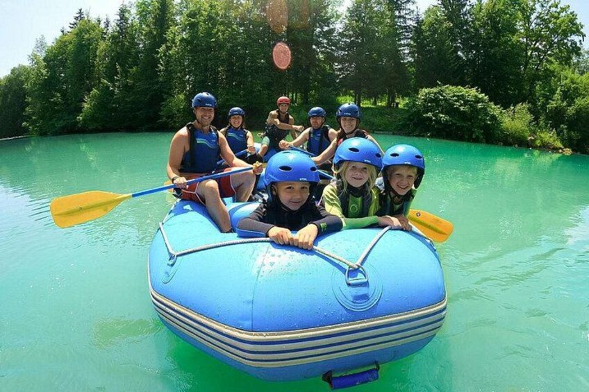 A group of people in a blue raft on a river surrounded by greenery. 2